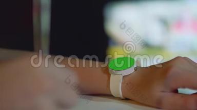 用绿色屏幕聚焦在女孩的左手上的白色手表，用女孩`的右手去聚焦笔